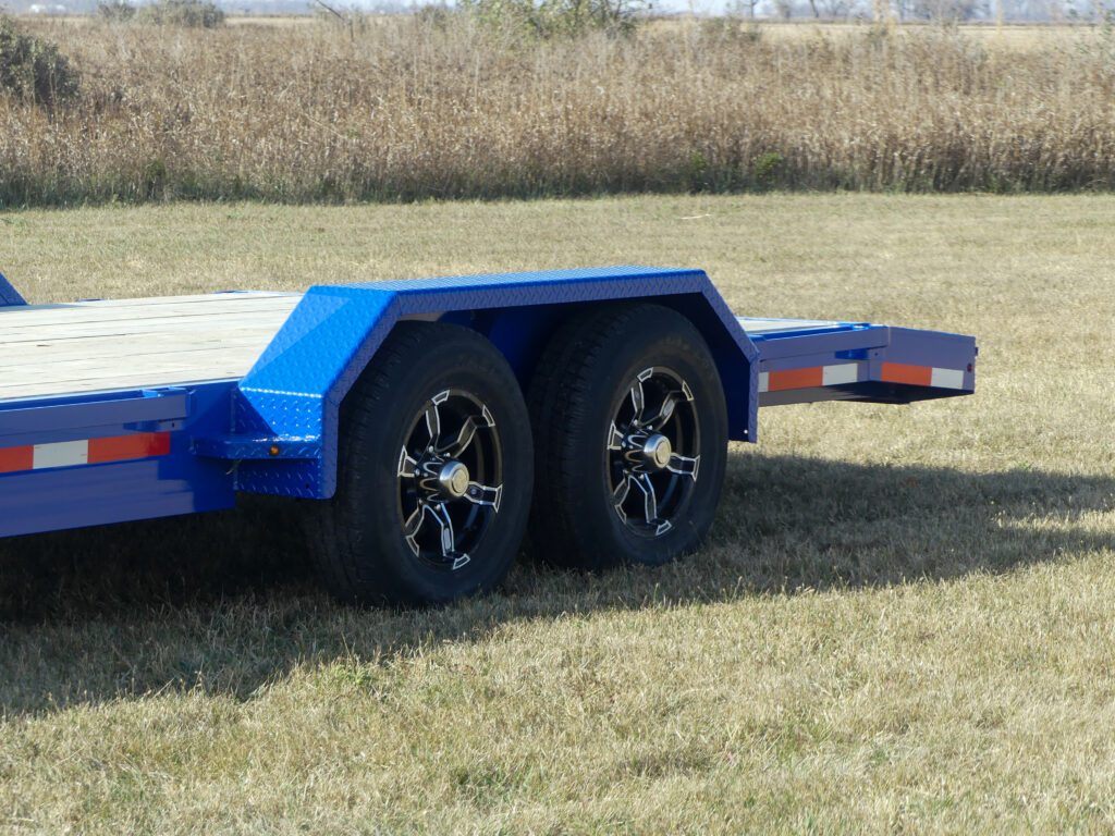Two black tires mounted on steel rims, attached to a blue utility trailer.